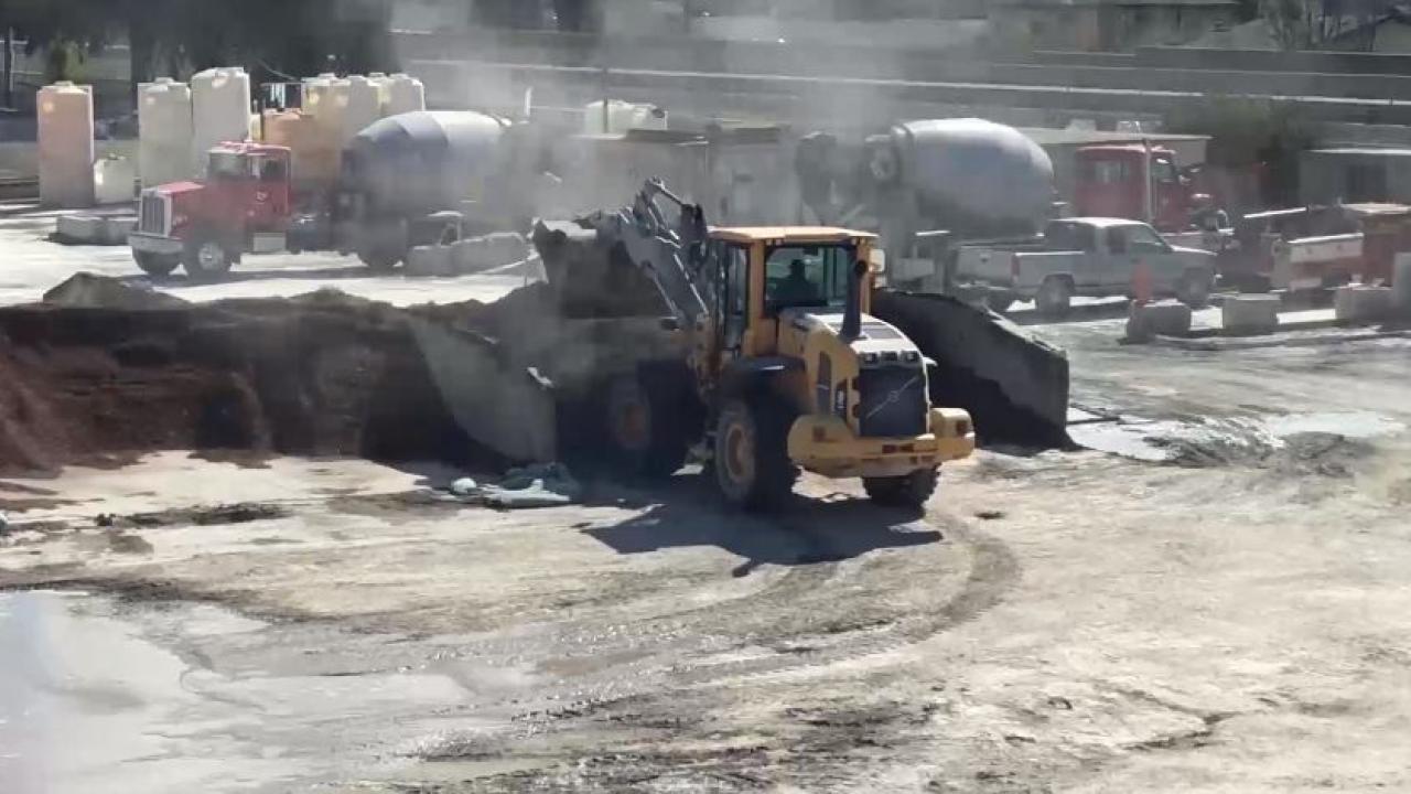 Image: a concrete plant featuring large vehicular equipment and visible dust plumes.