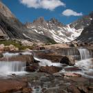 Image: a photograph of small, rushing falls of water over rocks at Titcomb Basin Cascade.